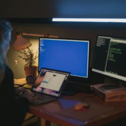 woman sitting in front of multiple computers dealing with mutli factor authentication